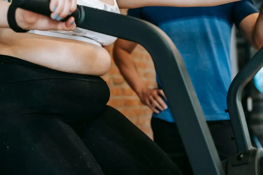 Close-up of a plus-size woman exercising on a cycle machine with instructor guidance in a gym.